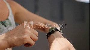 Redhead athlete syncs smart watch, readies for workout in outdoor gym. Fitness enthusiast monitors performance stats. Advanced wearable tech aids sports, track progress. Slow motion.