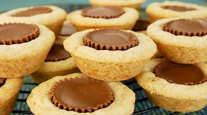 Link to recipe: https://www.joyofbaking.com/PeanutButterCupCookies.html Peanut Butter Cup Cookies look like miniature tarts and, in fact, are baked in miniature muffin tins. They start with a peanut butter cookie batter. Once made, you place about a tablespoon of the batter into each miniature muffin cup. The batter is baked until set around the edges but still soft in the center. At this point the cookies are removed from the oven and all that is left to do is to place one miniature peanut butt