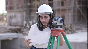 Indian Construction female Worker Using Theodolite Survey Optical Instrument for Measuring Angles in Horizontal and Vertical Planes on Construction Site.Asian Worker Making Project using site plans.