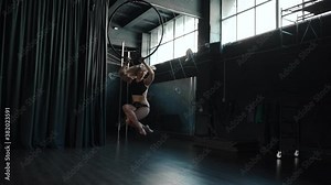 Young adult female using aerial hoop, spin around in circus