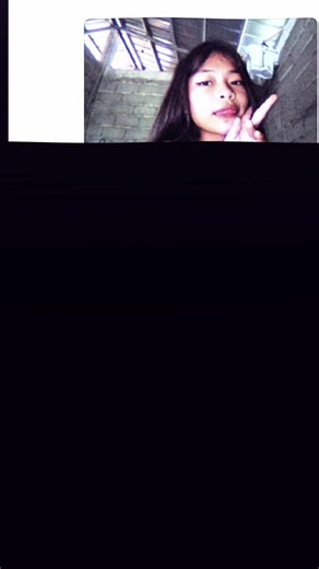 PROMPT:Vertical, realistic low-light phone selfie in a dim bedroom at night. Same face as reference (no changes). Cool bluish-purple screen glow lighting on a pale face; background mostly dark with beige blackout curtains on the left. Sleepy, cozy, late-night lo-fi vibe. Close-up, slightly low angle. Subject lying on stomach, propped on a grey pillow with subtle pattern. Messy black bedhead hair with wispy bangs. Soft, dreamy/blank stare, mouth slightly open. Hand near face, index finger touchin