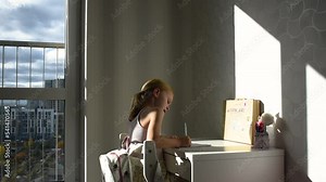 Cute smart primary school child girl learning writing doing homework sit at home table, writes prescriptions, little preschool kid studying alone making notes, children elementary education concept.