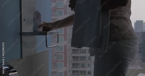 Housekeeper placing fresh towel in hotel bathroom with following view of bath with foam against city view in the window. Bangkok, Thailand