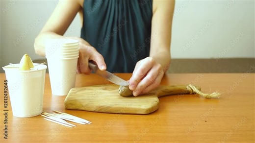 Woman begins trimming bottom of unpeeled avocado pit during home germination setup preparation. Represents plant propagation hacks, indoor gardening routines, and experimental seed starting techniques
