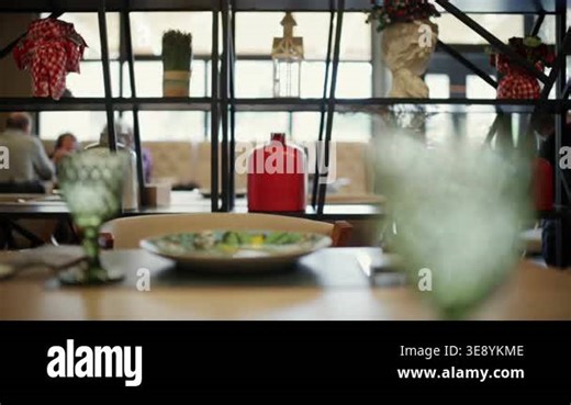 Stylish modern European restaurant interior with decorative shelves, plants, and table settings Stock Video Footage - Alamy