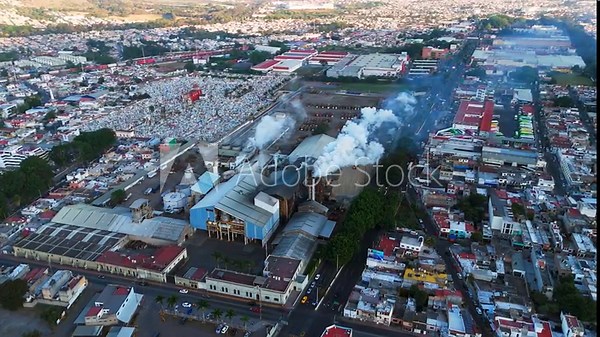 Sugar mill factory processing sugarcane and releasing polluting smoke into the urban environment