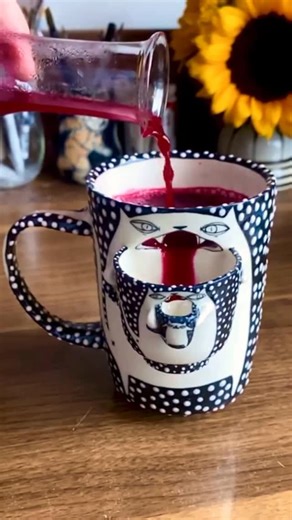 Love in Pottery on Instagram: "Maliya Travers-Crumb (@mtcpottery) is a ceramic artist based in New York whose illustration background flows straight into her clay work. As a potter, she makes playful pottery—pots, mugs, and earrings—often starring expressive animals (especially cats) that turn functional ceramics into bright, funny art. Maliya showcases one of her most hilarious ceramics builds: a black-and-white kitty mug that “pours” (or maybe barfs 😹) berry juice into a cup… inside another c