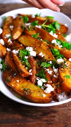 These Greek fries are baked in extra virgin olive oil and finished with flavors like garlic, oregano and feta. Add a side of homemade Tzatziki for dipping! | The Mediterranean Dish