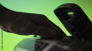 A man inserts a laser cd disc into an old music player on a green background. Hand close up. Retro technique. Previous generation of audio systems