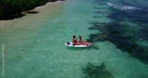 Two girl models on paddle board on bikini against the current in an exotic beach in the Caribbean 4K