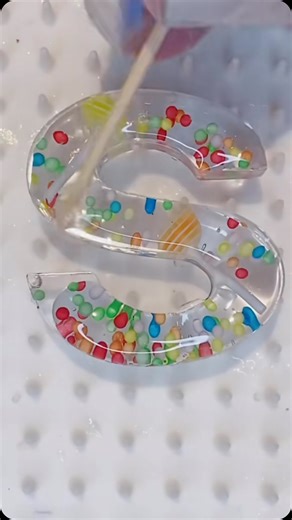 7.2K views · 192 reactions | S is for shiny ✨ Tiny lollipops, sprinkles, and all the shiny goodness—because details make everything sweeter! Who’s obsessed with the little things too?  #resinabout #ResinArt #UVResin #letterS #ResinLetter #SweetTreats #ResinArtist #MiniatureMagic #GlossyFinish #cuteandcolourful #spin | Resin About | Facebook
