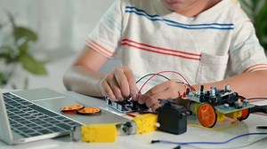 Asian kid boy plugging energy and signal cable to sensor chip with Arduino robot car, Little child remotely learn online with car toy, STEAM education AI technology course school learning lesson