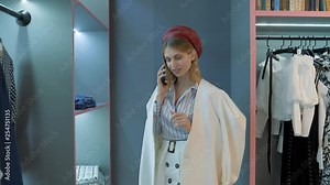 girl in red beret white jacket in a striped shirt talking on the phone where she says something pleasant from what she smiles in the showroom
