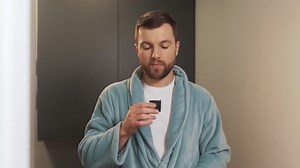 A handsome man in a bath robe put a special product in his mouth