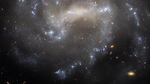 Close-up: Galaxy UGC 5460 in Ursa Major | Hubble FriendsofNASA.org: The sparkling spiral galaxy gracing this NASA/European Space Agency Hubble Space Telescope picture is UGC 5460. It sits about 60 million light-years away in the constellation Ursa Major. This image combines four different wavelengths of light to reveal UGC 5460’s central bar of stars, winding spiral arms and bright blue star clusters. Also captured in the upper left-hand corner of this image is a far closer object: a star just 5