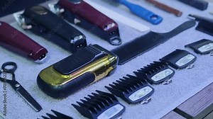 A close-up of the laid out hairdressing tools, including various types of clippers, attachments, scissors, combs and a straight razor. tracking shot Stock Video