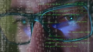 Male hacker working on a computer for cyber attack while green binary hacking code characters reflect on his face in a dark office room