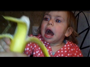 Little baby girl eating banana for the first time.