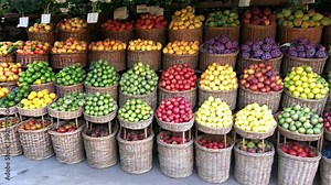 A large display of fruit is arranged in baskets, including apples, oranges, and pears. The fruit is colorful and fresh, and the arrangement is visually appealing