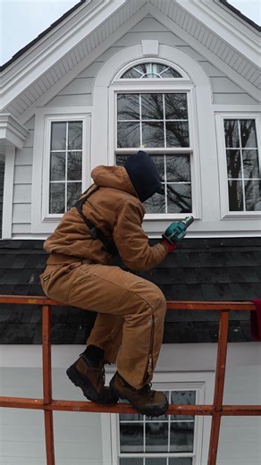 Trying to neatly caulk this dormer window from the boom lift rails — cold said no.