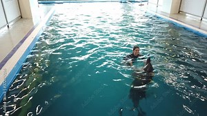 Girl swim with trained dolphin in dolphinarium