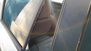 Premium stock video - Rear car window glass smashed and broken from attempted vehicle theft and robbery, shattered glass scattered on back car seats