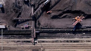 Loading of coal into railway cars. View from above. A large excavator loads coal into wagons. Coal warehouse.