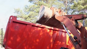Excavator bucket excavating earth and truck at construction site. Excavator bucket loads the ground. Excavator loads material on the truck, close up. Excavator working on a construction site. Stock Video
