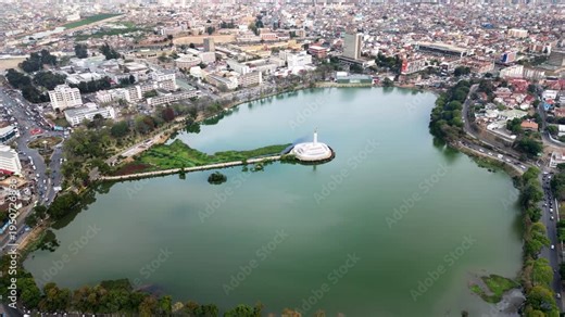 Aerial drone view of Lake Anosy with the central monument island and surrounding city of Antananarivo, showing the urban landscape of Madagascar's capital from above