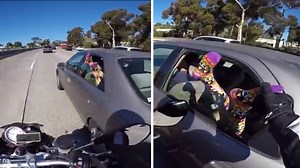 Motorcyclist grabs feet hanging out of car window on highway