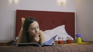 Relaxed woman reading a book lying on her bed - Free Stock Video