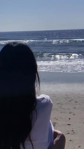 海辺の後ろ姿を撮影する女の子