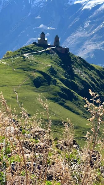 Trinity Church of Gergeti on the background of snow-capped mountains. View of the mountain peaks near Stepantsminda, Georgia. The ancient Christian church of Gergeti at the foot of Mount Kazbek. 4К