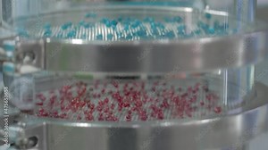 Many colorful granules bouncing on platform of sieve shaker machine for separation of particles: polymers, metal, powders, cereals, glass - separation process - close up view, selective focus