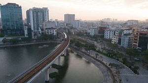 Hanoi, Vietnam - Jan 20, 2025: An aerial view of Hanoi at sunrise. A network of roads and elevated railway, with high-rise buildings and residential areas stretching towards the horizon.