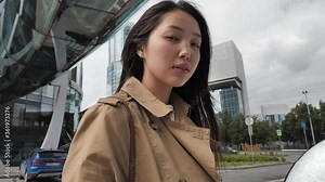 Beautiful young girl of Asian appearance walks and poses against the backdrop of cityscapes