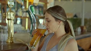 Happy beautiful caucasian woman drinking beer alone at the bar.She thinks by looking at the things around her as she enjoys the beer she drank. Solo entertainment concept.