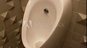 Standing toilet for men urinating. White Porcelain Urinal Hanging on Wall in Men Public Restroom. The process of releasing clean water to remove and clean male urine. No people