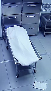 A late-night shift at a Miami hospital morgue took a shocking turn when a worker was startled by unexpected movement from a body she was preparing for storage — all captured on the facility’s security cameras. The footage shows the technician calmly checking inventory and closing one of the cold-storage drawers when the sheet-covered body on the gurney suddenly twitches. A split second later, the left leg visibly shifts, causing the sheet to slide. The worker freezes, then jumps back in fright. 