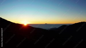 Beautiful aerial view of sunrise time with orange sunlight and silhouette of highland in Dieng Plateau, Wonosobo, Central Java. Shot in 4k resolution from a drone flying forwards