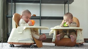 Asian twin babies sitting on safety chair, the chair can use for car seats, Two little baby waiting to eat at home