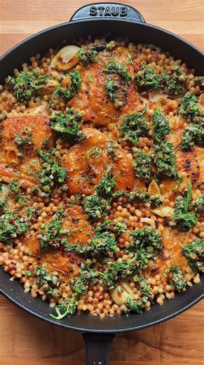 Carolina Gelen on Instagram: "ONE PAN GARLIC CHICKEN COUSCOUS — crispy chicken thighs, tender pearled couscous, plus a tangy herb sauce: the recipe I make the most often from Pass the Plate, out September 24!!! Preorder links in bio!!! #chicken #chickendinner #chickenrecipes #dinner #dinnerideas"