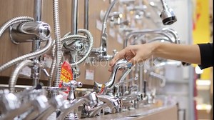 Female Hand Trying Faucets Mechanism at Plumbing Store. Items for Bathroom Shopping in Department Mall. Red Sale Special Price Tag Closeup. 4K.