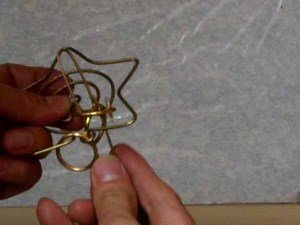 Metal wire and ring puzzle with handle shuttling through a principle frame