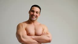 Young laughing muscular bodybuilder posing and looking at camera,...