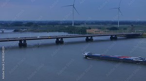 Cargo Vessel Cruising In The Hollands Diep River Towards The Moerdijk Bridges With Wind Turbines In The Distance In Netherlands. - aerial