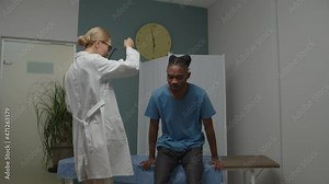 Skilled female doctor checking male patient by using stethoscope on man's back, detecting breathing problems indoors. Mature physician holding doctor's appointment in medical center