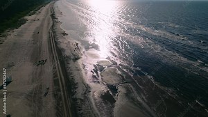 A top view of a Baltic beach and sea with sunlight reflecting in a pattern and detailed wave structures, creating a serene and picturesque scene. Location: Pärnu, Estonia