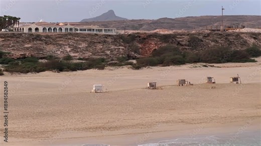 Panning view of sandy beach,parasol, beach loungers and background luxury resort, summer concept, Chaves beach in Boa Vista island, Cape Verde.