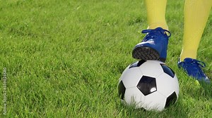 Athlete's Foot in Football Cleats on Soccer Ball. Feet of Football Player and Ball on Stadium Grass, Close up